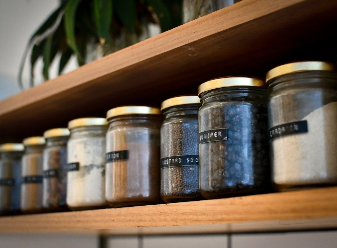 Glazen voorraadpotten met etiketten staan op een houten keukenplank